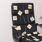 An office chair covered in post-it notes showing too many tasks for one person.