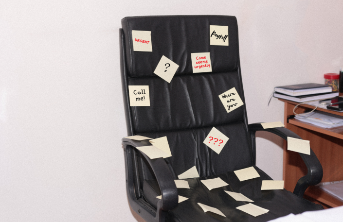 An office chair covered in post-it notes showing too many tasks for one person.